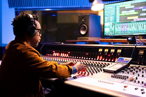 African american sound designer correcting tonal imbalances and white noise on audio recordings, music industry post production in studio. Control room expert editing tracks, mix and master.