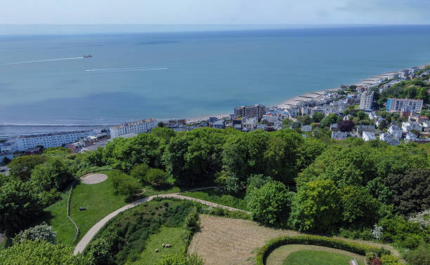Awe sunny Drone point of view from Hanging gardens in Le havre on nature and city and Plage (beach) and fishing ship \nmoving from  harbor and small speed motorboat moving to harbor. Several white residential buildings (apartment buildings)  near the Plage