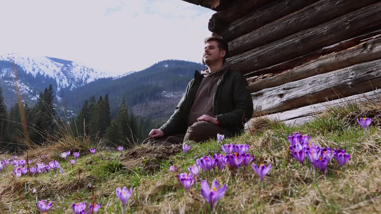 Man with Backpack Relaxing on Meadow of Blooming Safron Crocuses Admiring View of Tatras Mountains