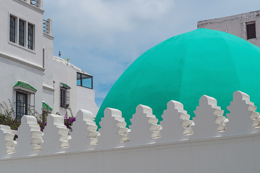 Decorative patterns on the tops of the wall of a muslim mosque with a bright green dome of the mosque.