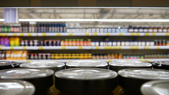 Many jam jars with metallic lids on a supermarket shelf close-up