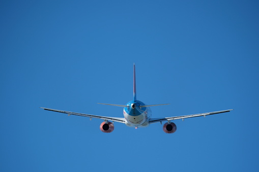 Plane flying away into the distance against a blue sky