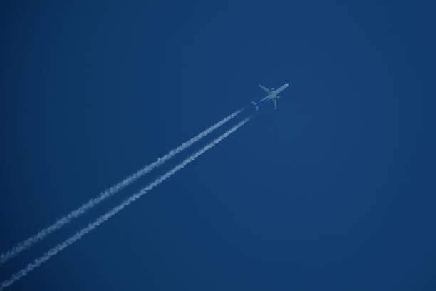 Airplane in the blue sky with contrails.