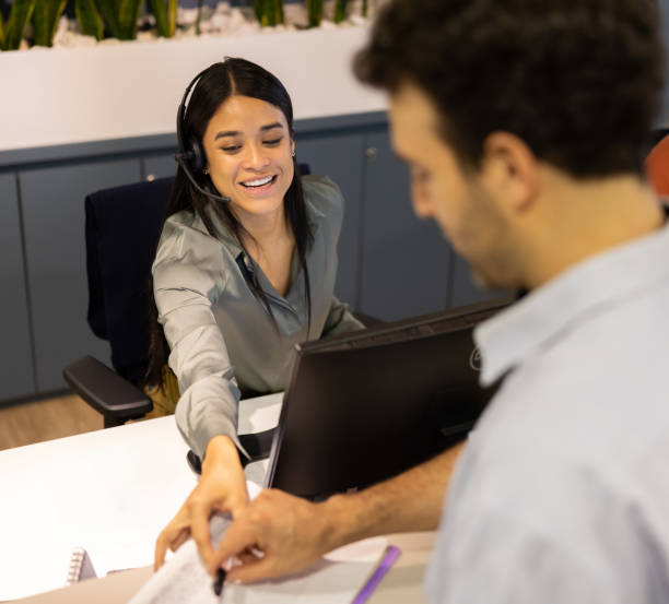 istock Friendly receptionist asking customer to fill a form at the office 2147591233