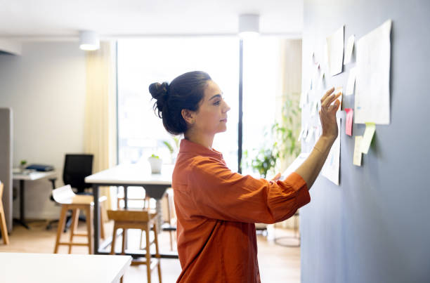 istock Businesswoman brainstorming and writing ideas on sticky notes 2147591271