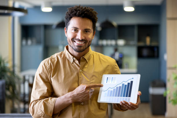 Business man at the office pointing at a growth graph on a digital tablet