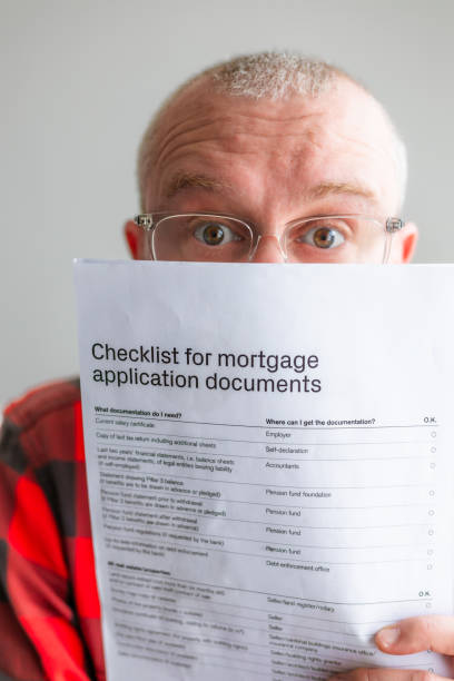 istock Mid adult man reading mortgage application documents at home 2147591944