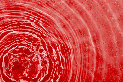 drops on water with circles on a red background close up