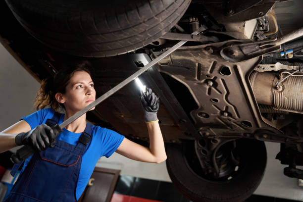 istock Female in blue uniform inspects a car raised on lift 2147592925