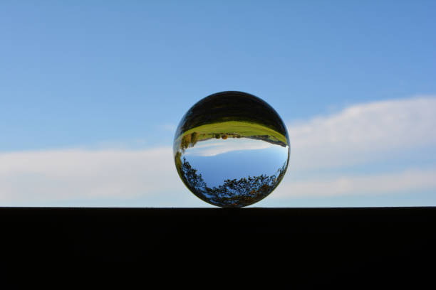 istock Green landscape reflected in a sphere, with blue sky 2147593895