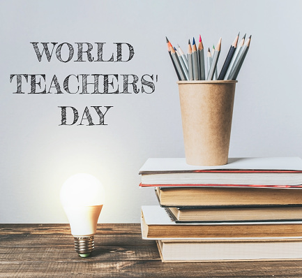 A stack of books with a light bulb on top of them. The image is titled World Teachers' Day