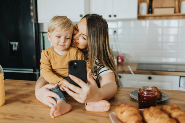 Mother and son taking selfie during breakfast at home