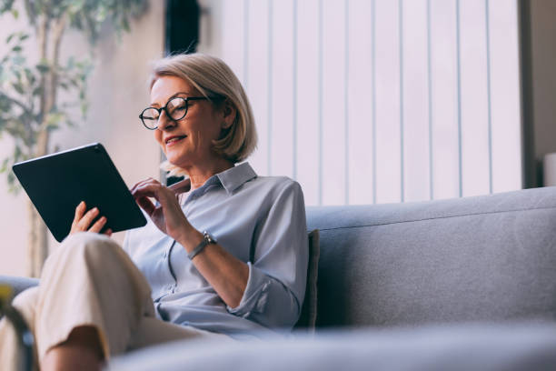 istock Senior Woman Relaxing on Sofa with Digital Tablet 2147595511
