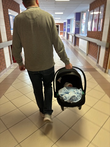 A new father leaving hospital for the first time with his new born child