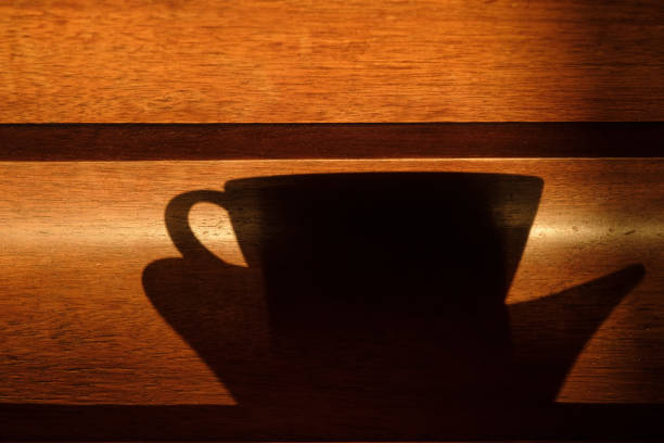 The shadow of a Cup and saucer on a wooden surface on a Sunny day.