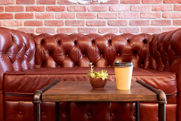 Paper cup with coffee and pot with flower on the table. British style