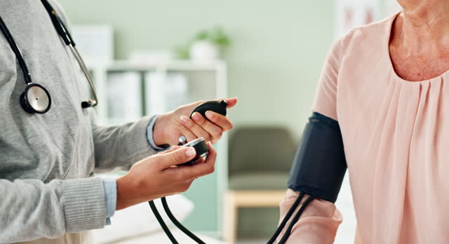 Doctor, hands and patient with blood pressure machine for exam or monitoring heart rate at the clinic. Closeup of person, cardiologist or medical worker measuring pulse for hypertension or healthcare