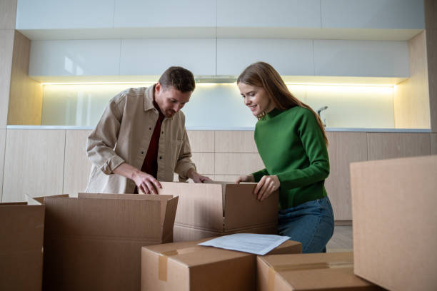 istock Merry happy homeowners unpacking carton boxes in new flat. Relocation day into purchased apartment 2147604507