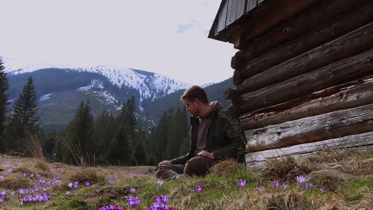 Man with Backpack Relaxing on Meadow of Blooming Safron Crocuses Admiring View of Tatras Mountains