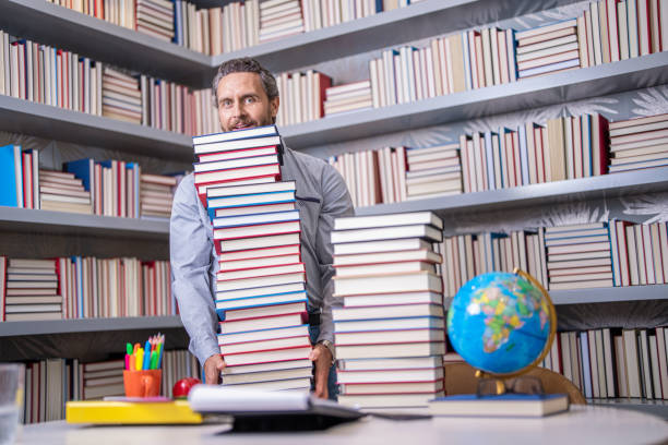 istock Hispanic teacher in college. Man with books in library. Knowledge and education. school library. Teachers day. Teacher in school classroom. teacher with book in library classroom. Literary escape 2147606671