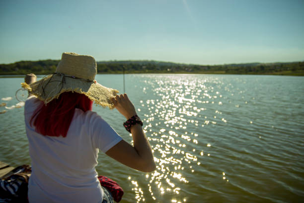 Woman is wearing straw hat looking on the beautiful lake