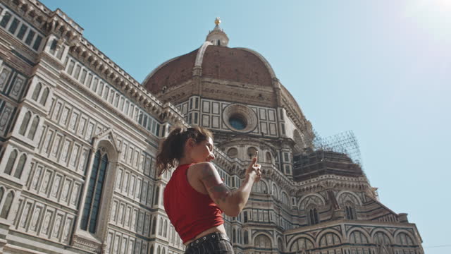 Cathedral of Saint Mary of the Flower at sunrise or sunset, Italy, Florence. Tourist woman taking selfie pictures on famous cathedral background on smartphone. Tourism, holidays, vacation concept.