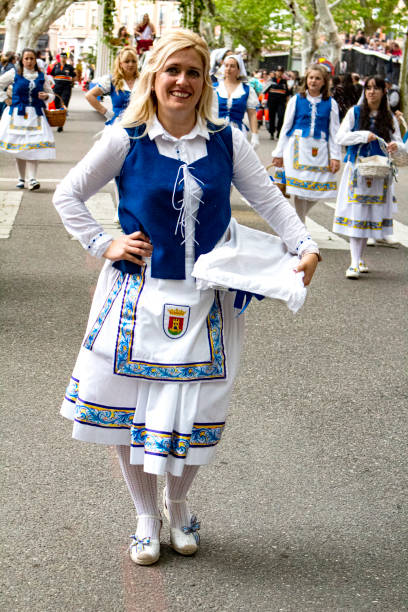 Girl dressed in typical regional costume and with a bouquet of flowers as an offering at the Mondas festival.  Festival of the Mondas is an ancestral celebration in Talavera de la Reina, recognized as a Festival of National Tourist Interest since 2009. This festival has roots that date back to the veneration of the goddess Ceres in Roman times, and has evolved through centuries to become a cultural event full of color and tradition. Every year, the community gathers to decorate the streets and pay tribute to Our Lady of the Prado with a procession that brings offerings to the Virgin with songs and dances
