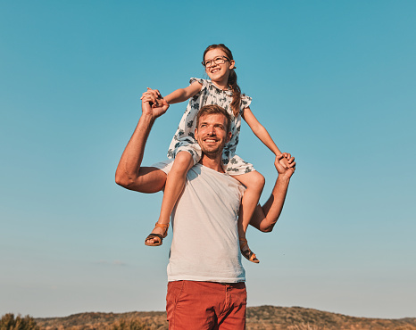 Portrait of a young happy father with his daughter having fun outdoors