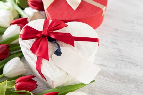 Mother’s Day and Valentine’s Day concept with red and white tulips and heart shaped gift box