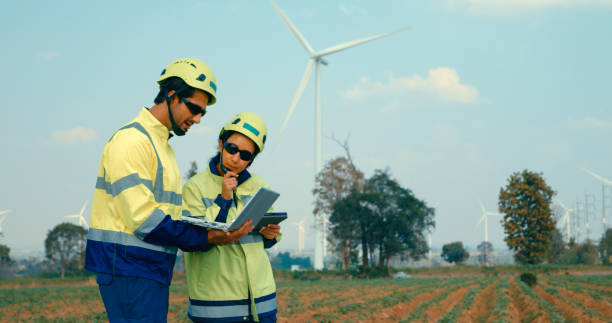 istock Renewable energy engineers are actively discussing over laptop at wind farm, pointing out details on screen. Green ecological power generation wind sustainable energy. 2147612479