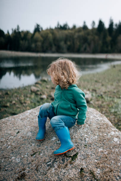 istock Toddler Sitting on Large Boulder at the Beach 2147613240