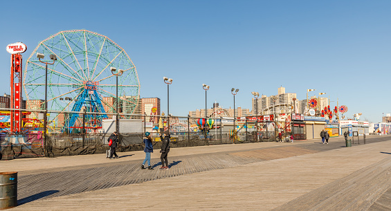 New York City, Brooklyn, USA - February 18, 2023: street atmosphere in front of closed Coney Island attractions with people walking on a winter day