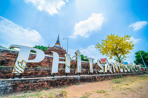 Text letter light Phitsanulok city and Golden Cassia fistula flowers at Park in Phra Chedi Luang in Temple (Wat Ratchaburana) is a major tourist attraction in Phitsanulok Thailand.daytime blue sky