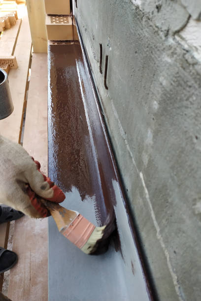 istock A man paints a metal corner with brown paint, working on a construction site. 2147615082