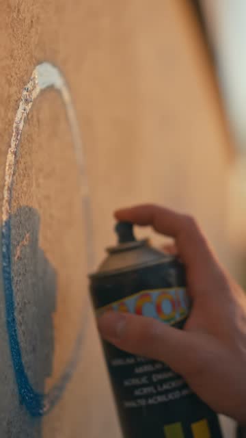 SLO MO Closeup of Hand of Unknown Man Doing Graffiti on Wall with Paint Spray Can at Sunset