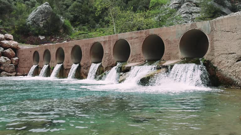 Captivating view of a bridge, dam over a small river with vibrant green waters, highlighting the serene beauty. Footage showcases bridge, dam integration with nature