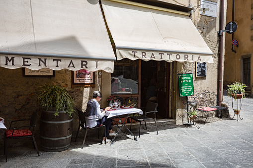 Tuscany, Arezzo  May, 2022: Cityscape. Small street cafe Trattoria Mazzoni with some visitors.