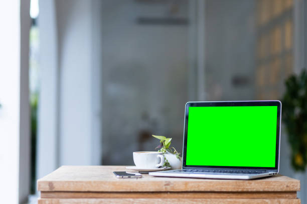 istock Mockup of laptop computer with empty screen with coffee cup and smartphone on table of the coffee shop background,Green screen 2147620658