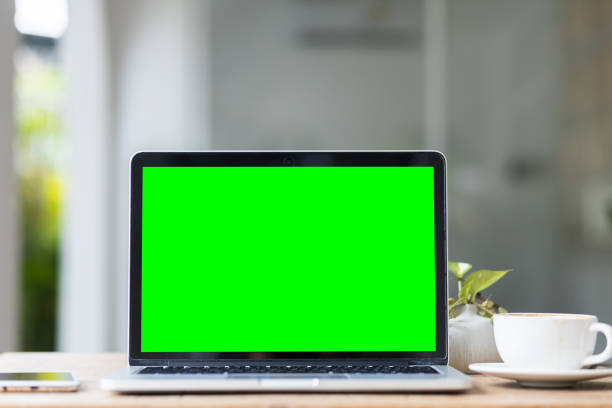 istock Mockup of laptop computer with empty screen with coffee cup and smartphone on table of the coffee shop background,Green screen 2147621372