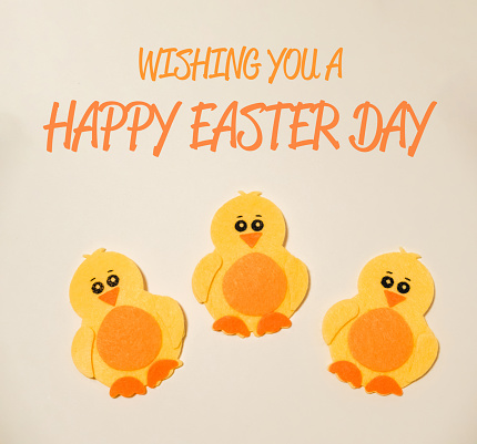 Three yellow chicks are sitting on a white background. The image is a greeting card for Easter. The message is wishing the recipient a happy Easter day