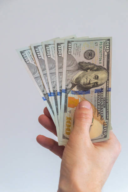istock 5 one hundred US dollars held in his right hand. 2147627244