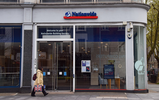 London, UK - April 8 2024: a woman walks past a Nationwide Building Society branch in Central London.