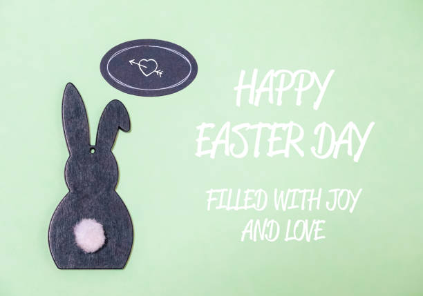 A rabbit is on a green background with a heart and the words Happy Easter Day. The rabbit is filled with joy and love