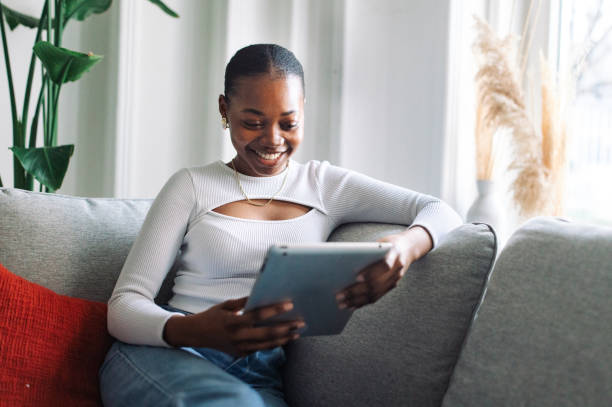 istock Smiling woman using tablet on couch at home 2147633214