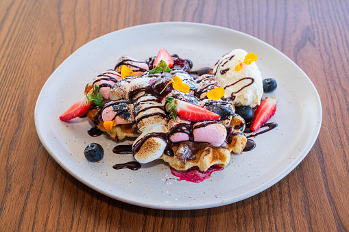 Hong kong or bubble waffle with ice cream, fruits, chocolate sauce and colorful candy