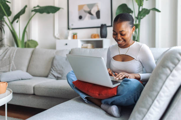 istock Smiling black woman using laptop at home 2147637000