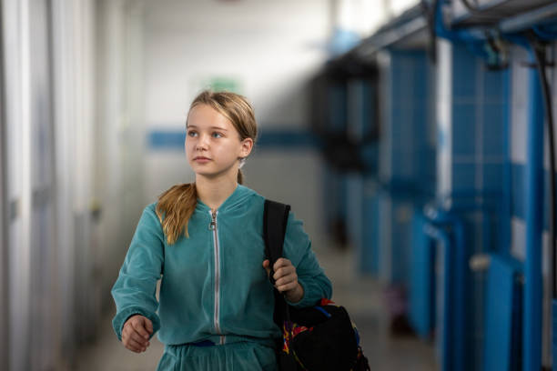 Medium shot. Side view. Cute little girl walking to school with a teddy bear sticking out of her backpack on gradient background. Professional shot in 4K resolution. 060. You can use it e.g. in your medical, commercial video, business, presentation, broadcast