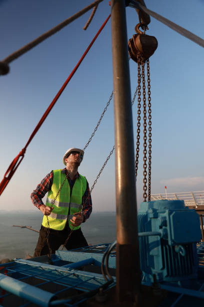 at sea, on board ship - december 21, 2022 : crew member of commercial cargo ship performing deck maintenance work while chipping  and buffing at poop deck of ship using a grinder buffing machine
