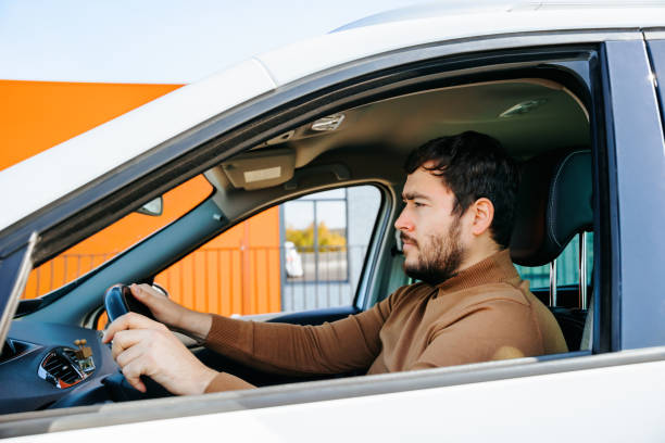 istock Handsome bearded young man driving a car is behind the wheel. 2147640535