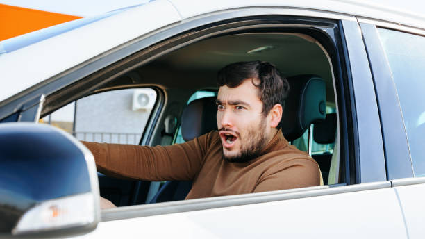 istock Front view of a young guy, a man grimaces while sitting in a car, apparently something excited him. 2147640561
